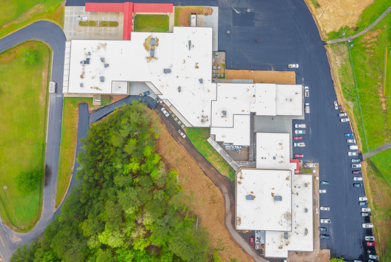 An aerial view of a large building with a parking lot in front of it.