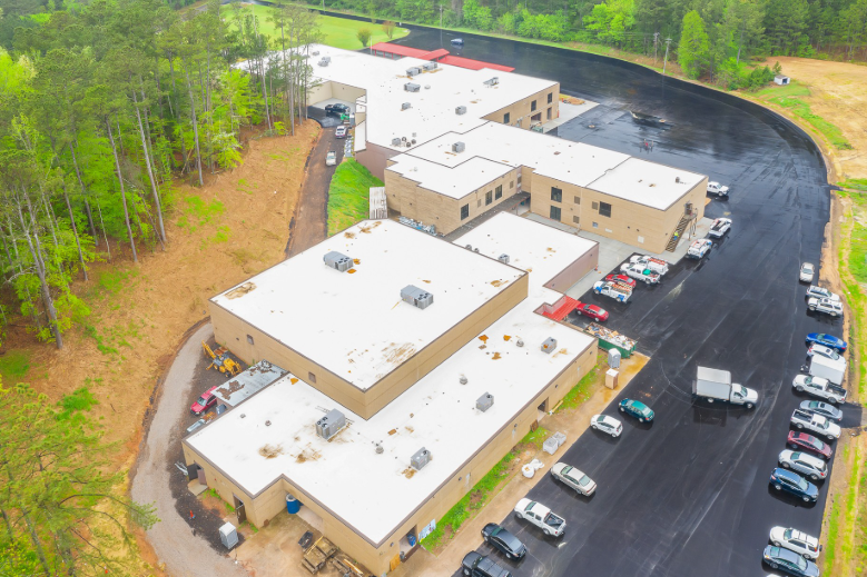 An aerial view of a large building with a lot of cars parked in front of it.