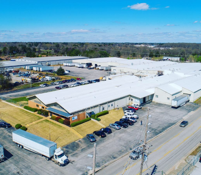 An aerial view of a large warehouse with trucks parked in front of it