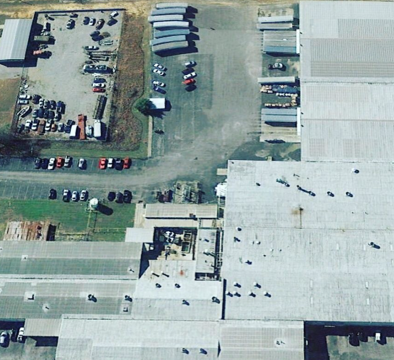 An aerial view of a large building with a lot of cars parked in front of it