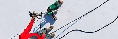 A person in a red jacket is working on a roof.
