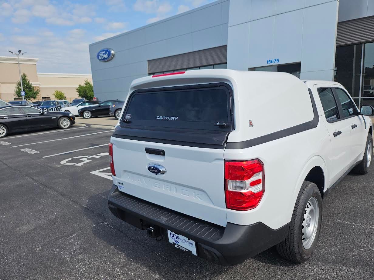 White Ford truck with a cap parked in front of a Ford dealership.