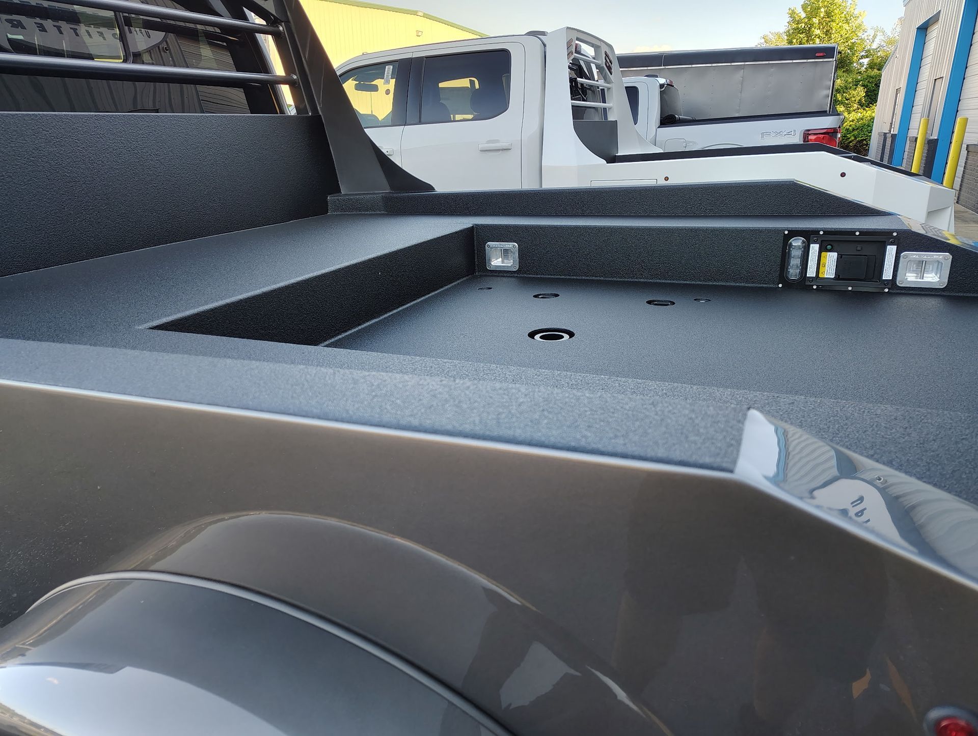 Gray truck bed with textured coating, metal trim, and lights.