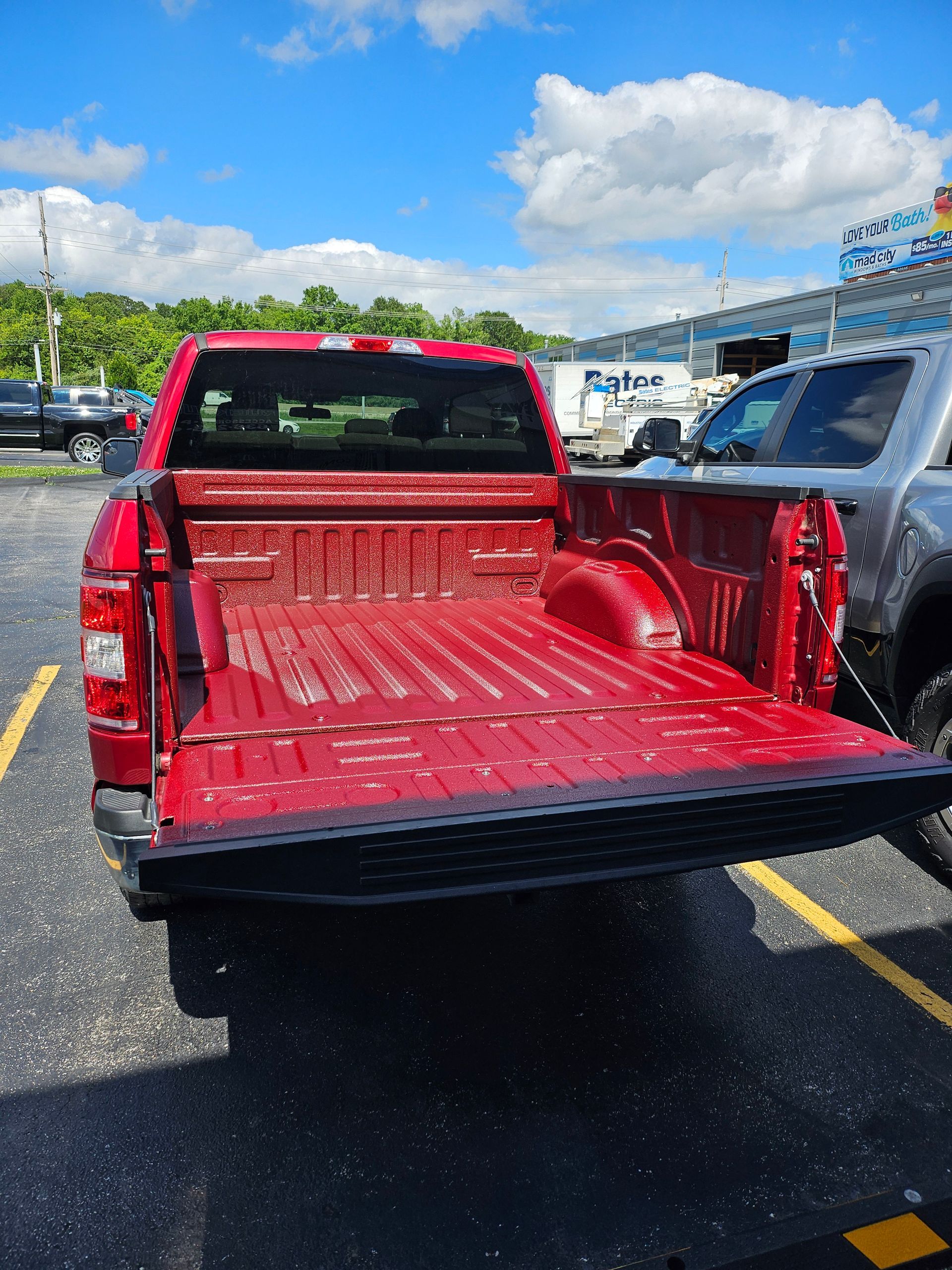 Red pickup truck bed open, parked in a lot under a blue sky.