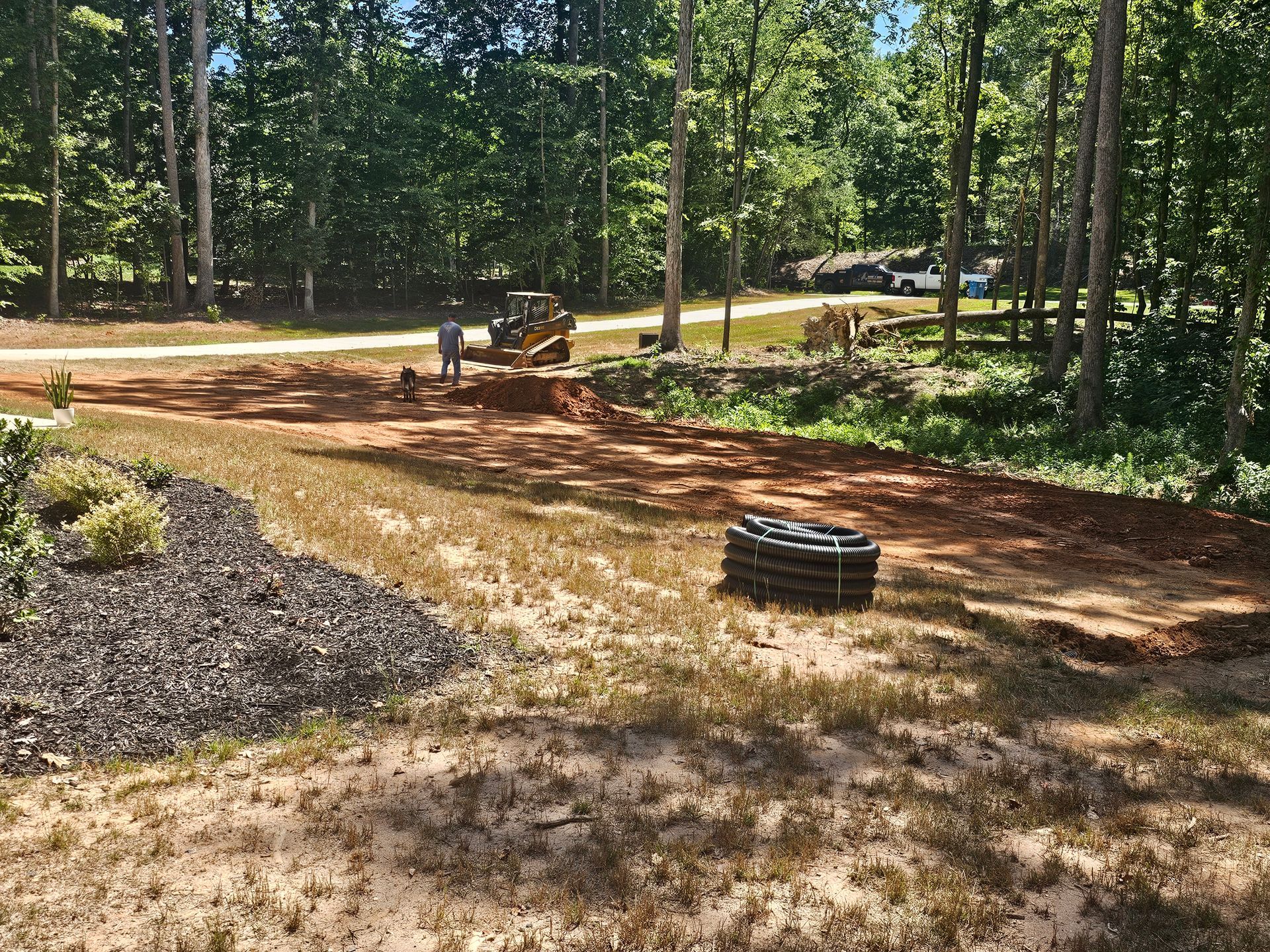 A man is standing next to a bulldozer in a dirt field.