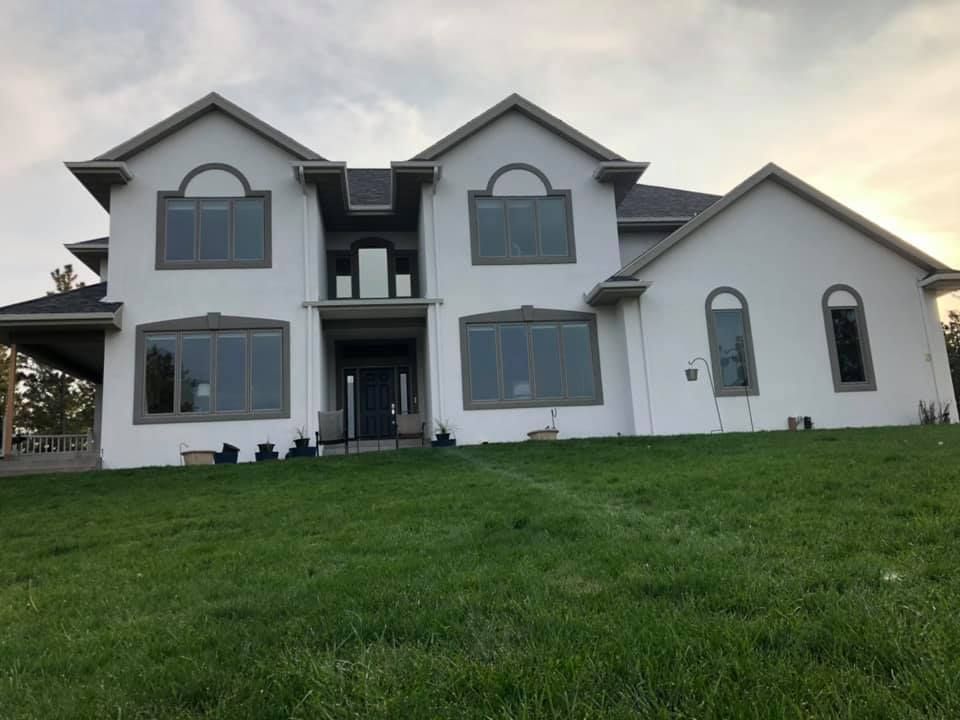 Two-story white house with green lawn; gray roof, windows, and trim.