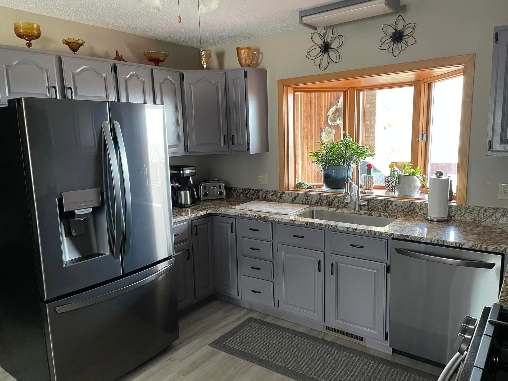Gray kitchen with stainless steel appliances, granite countertops, and a bay window.