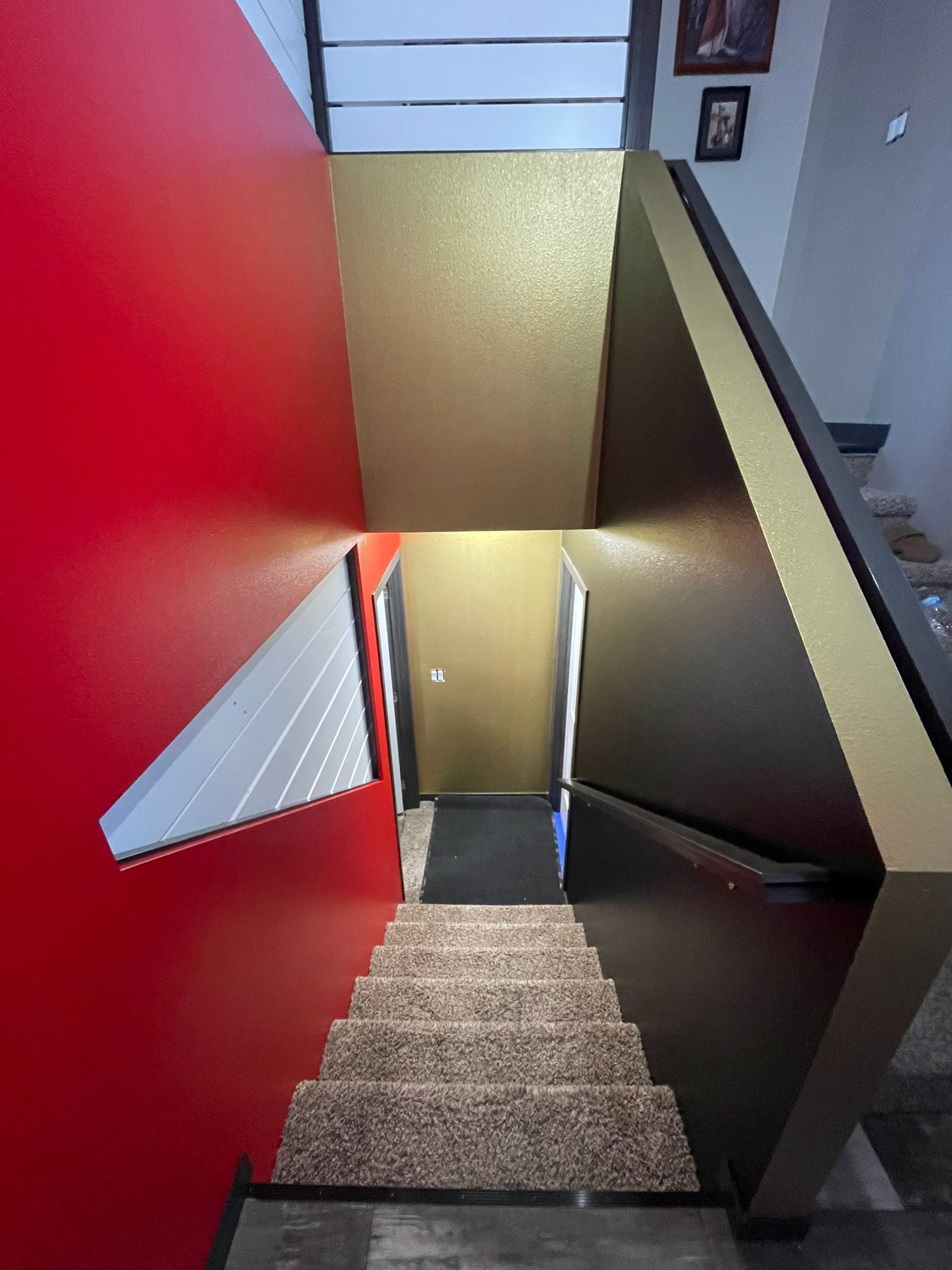 Stairwell with red and gold walls, descending steps, and a landing.