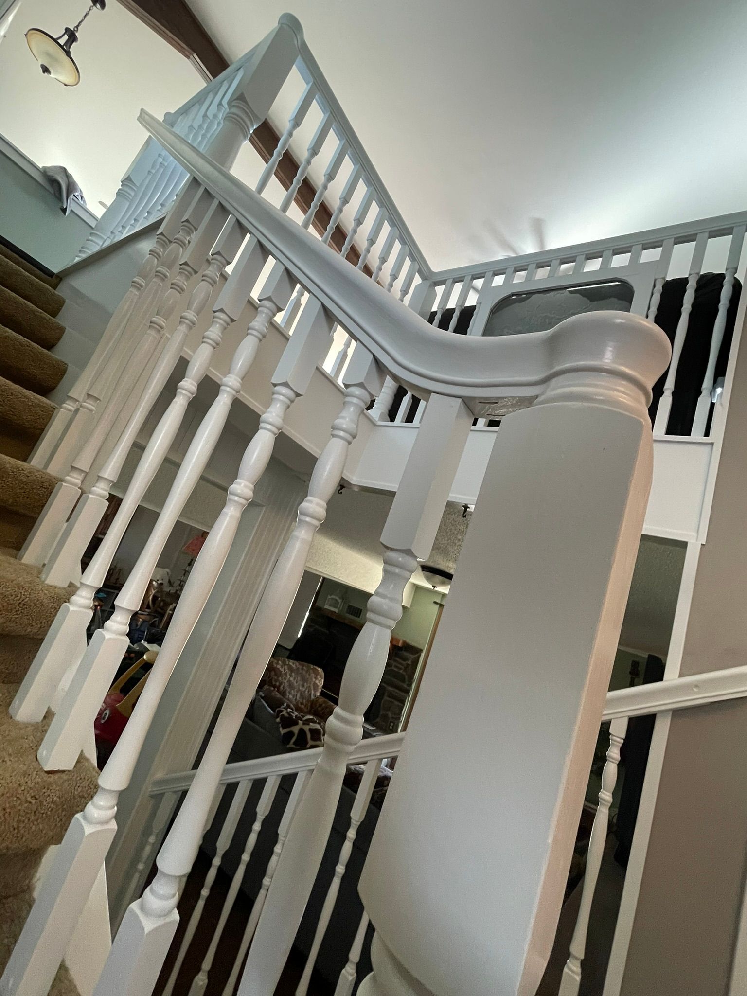 White staircase with carpeted steps and railing, viewed from above.