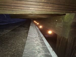 View from beneath a wooden structure, with a row of glowing lights along the center.