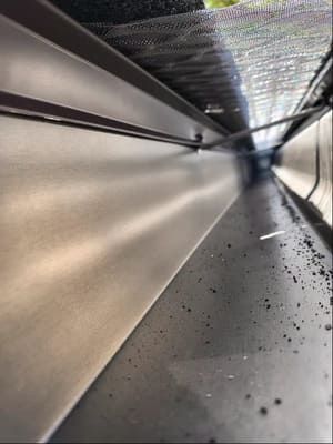 Interior view of a gutter, showing metal surfaces and some debris.