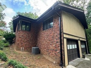 Two-story brick and tan home with black trim, two garage doors, and a small yard.