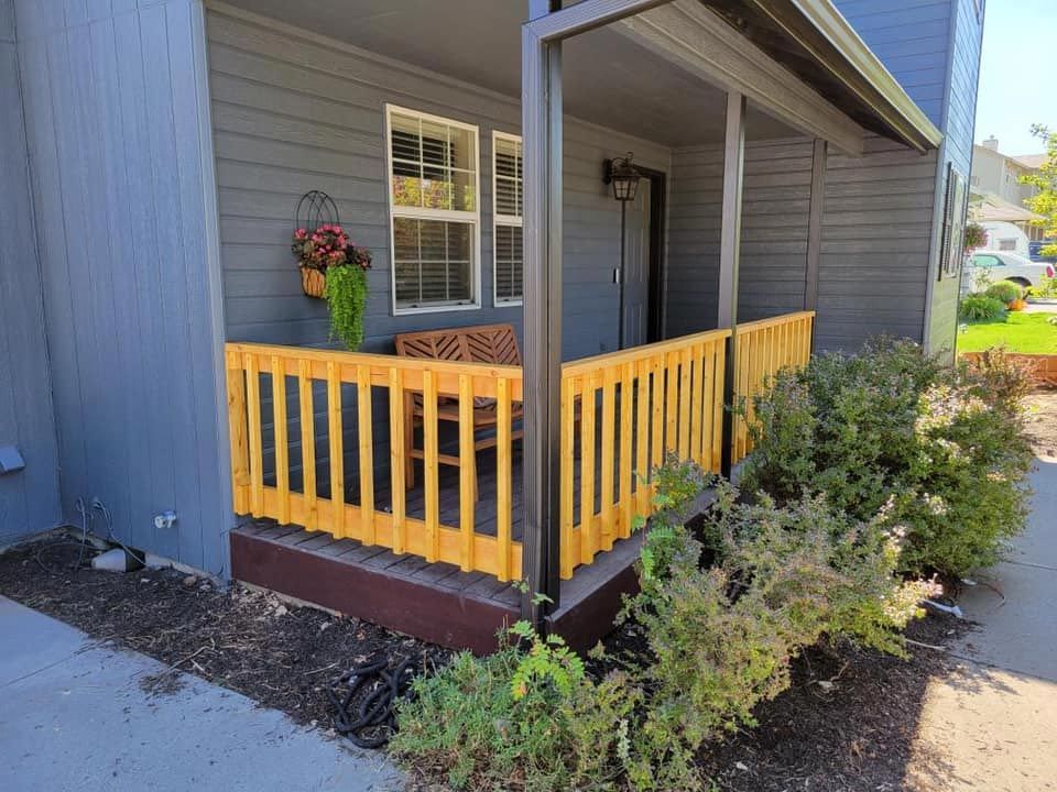 A gray house with a yellow porch and a yellow railing.