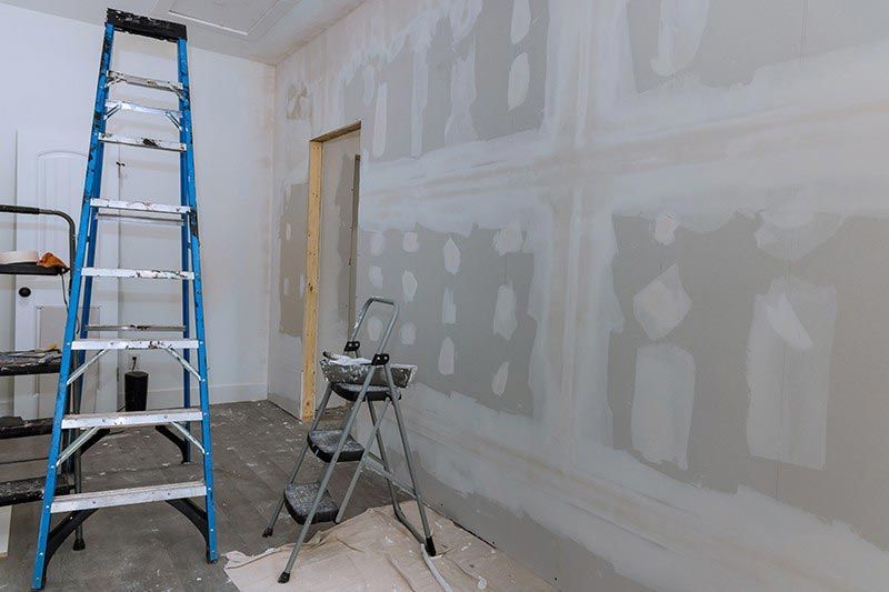 A room is being remodeled with a ladder and a step stool.