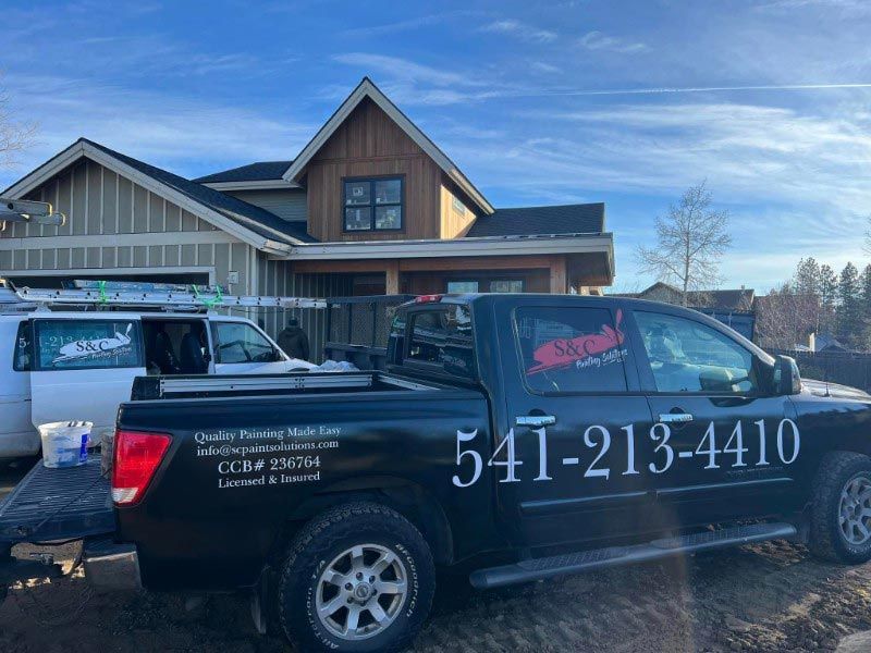A black truck is parked in front of a house.