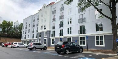 A parking lot in front of a large building with cars parked in front of it.