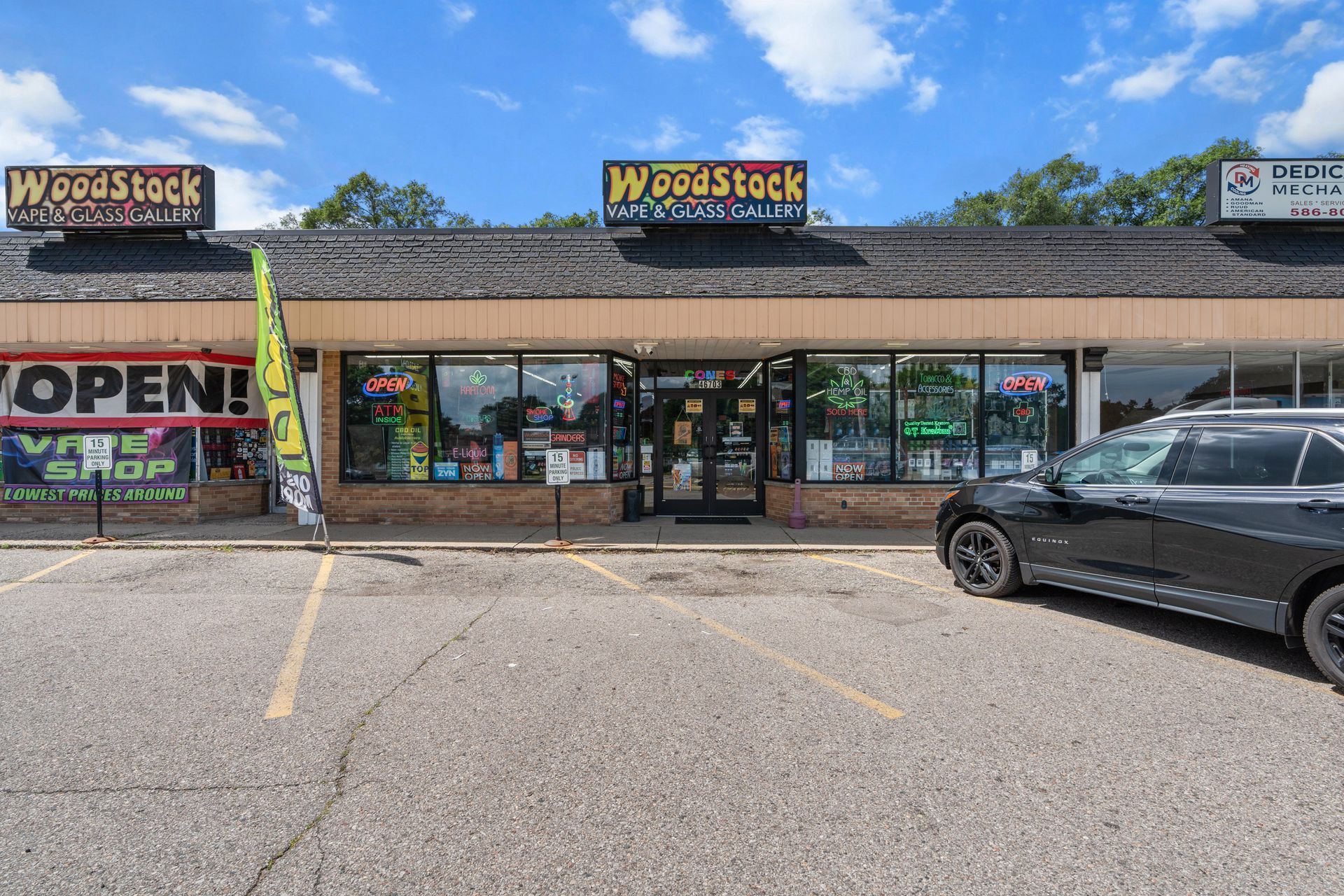Woodstock Smoke Shop storefront with black car parked outside.