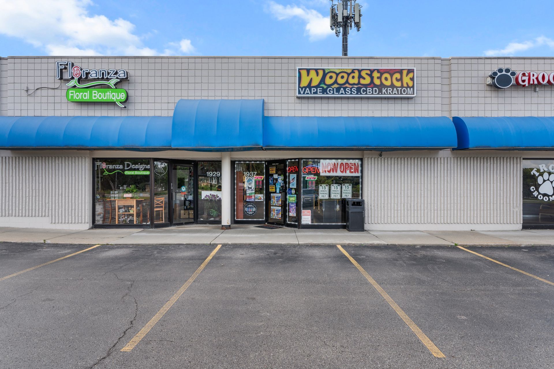 Storefront with Woodstock sign; blue awning, shops in a strip mall, parking lot.