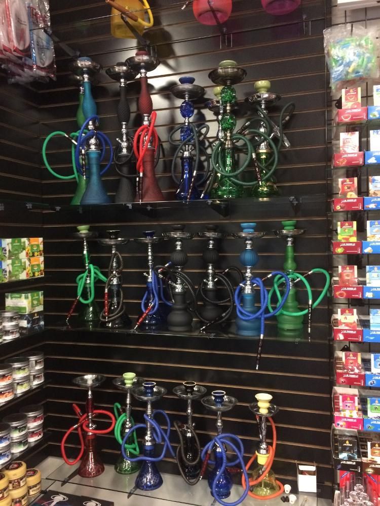 Shelves display colorful hookahs with hoses in a shop.