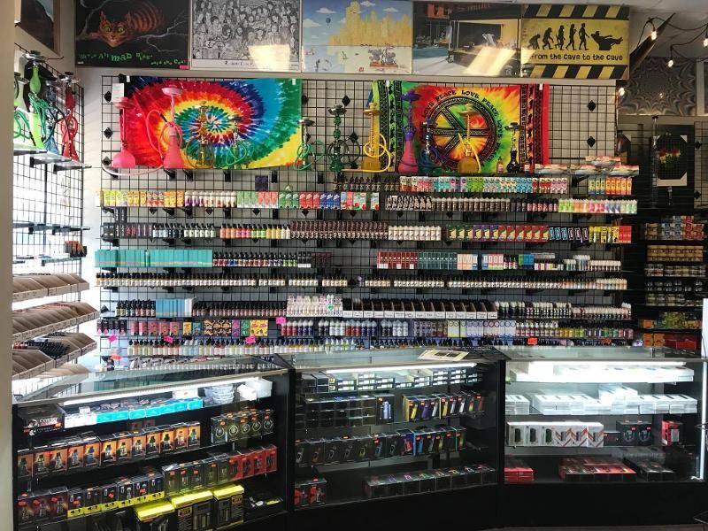 Interior of a vape shop, shelves filled with vape products, colorful artwork on the wall.
