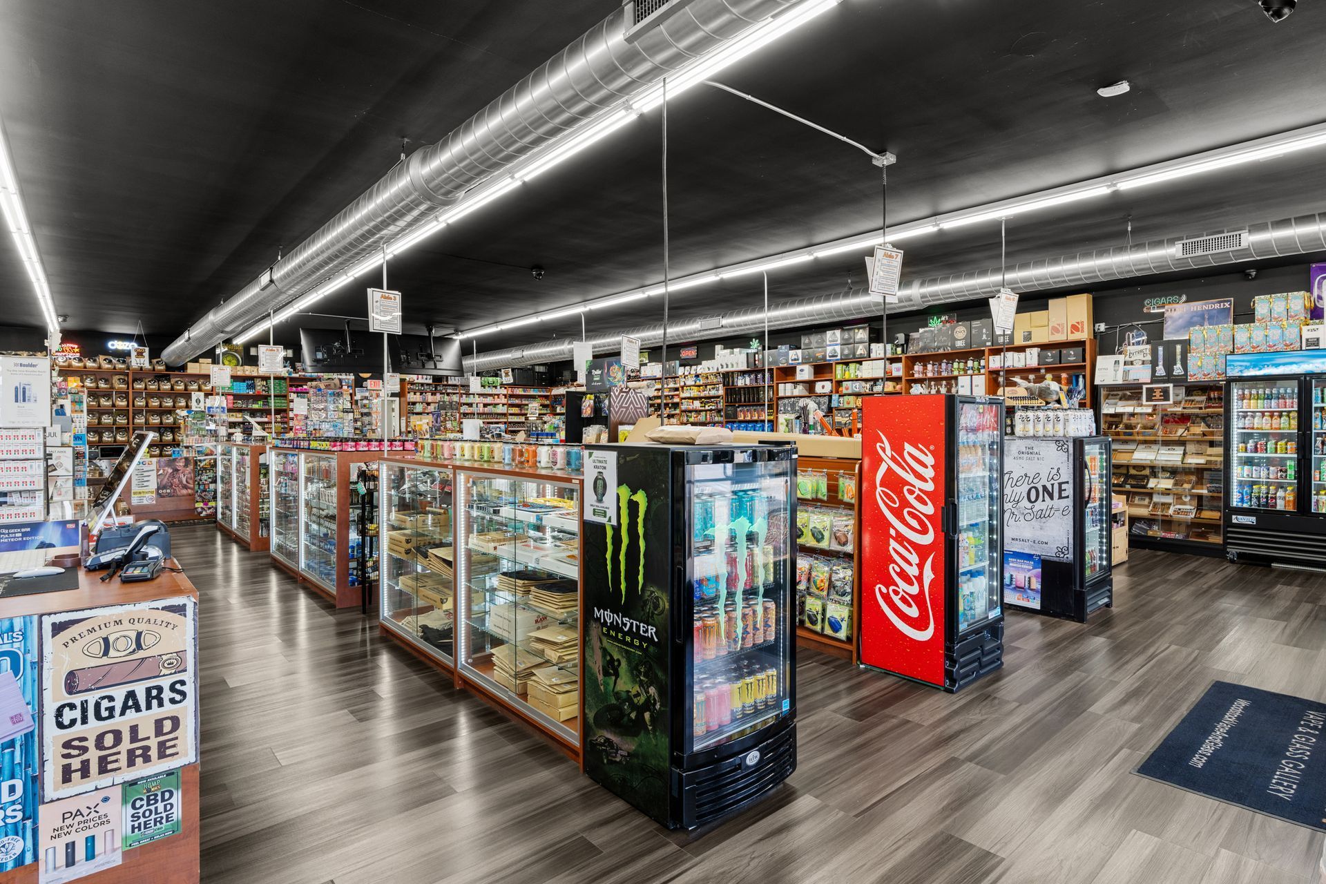 Interior of a store selling various products, including drinks and cigars. Coolers and display cases line the aisles.