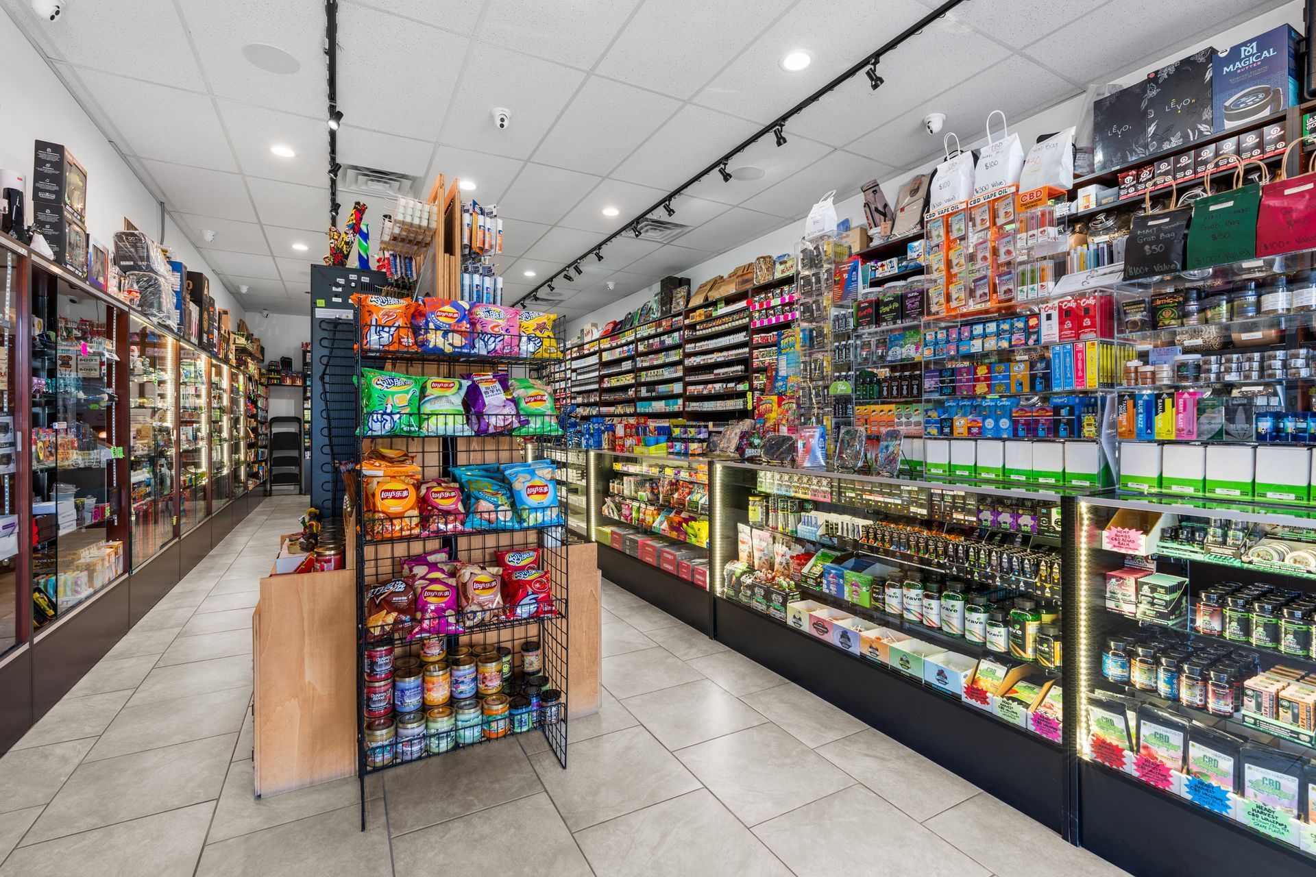 Interior view of a convenience store with various snacks, drinks, and merchandise displayed on shelves and in display cases.