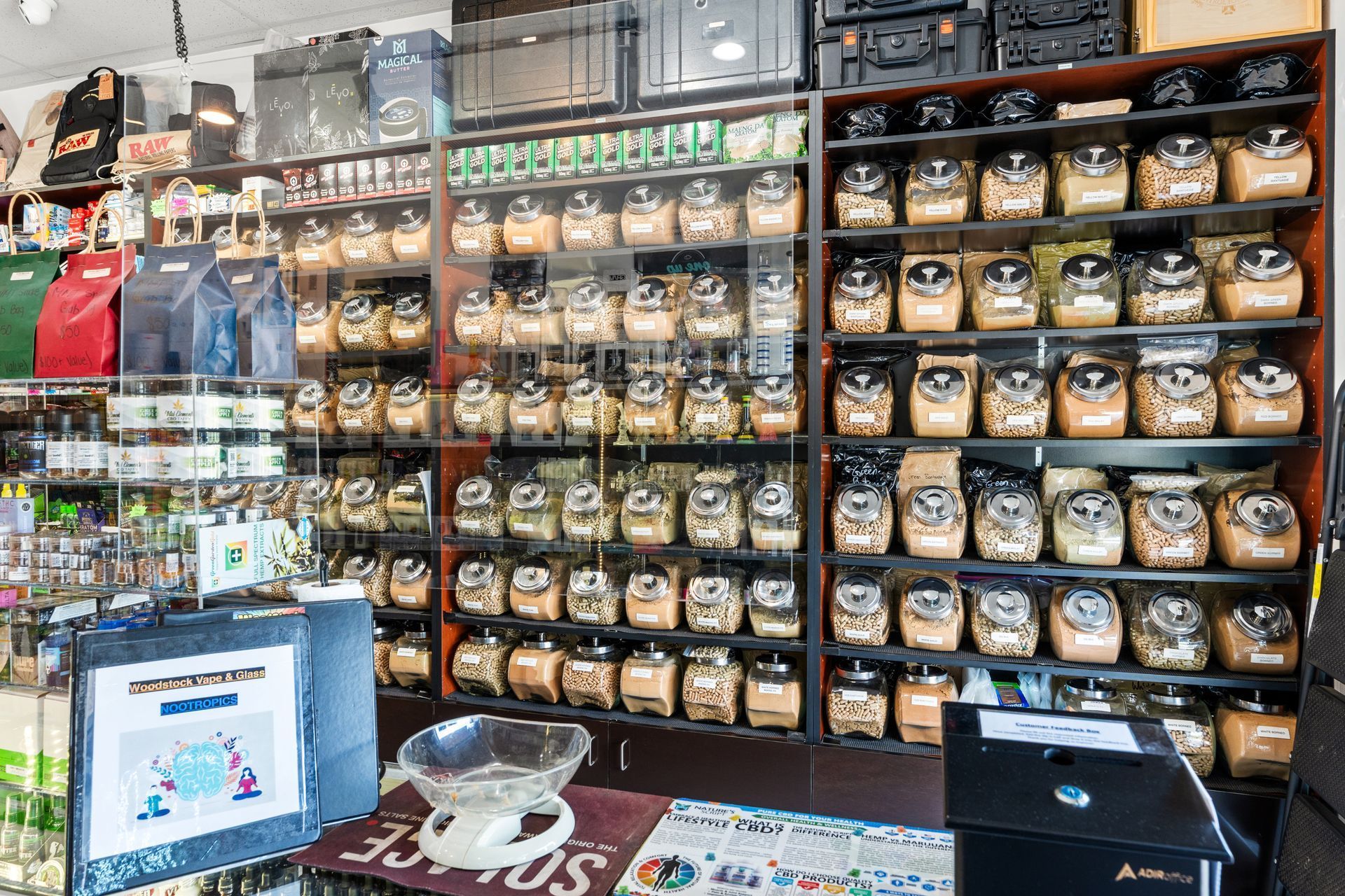 Shelves of jars and bags in a shop filled with tea or spices. A scale sits on a counter.