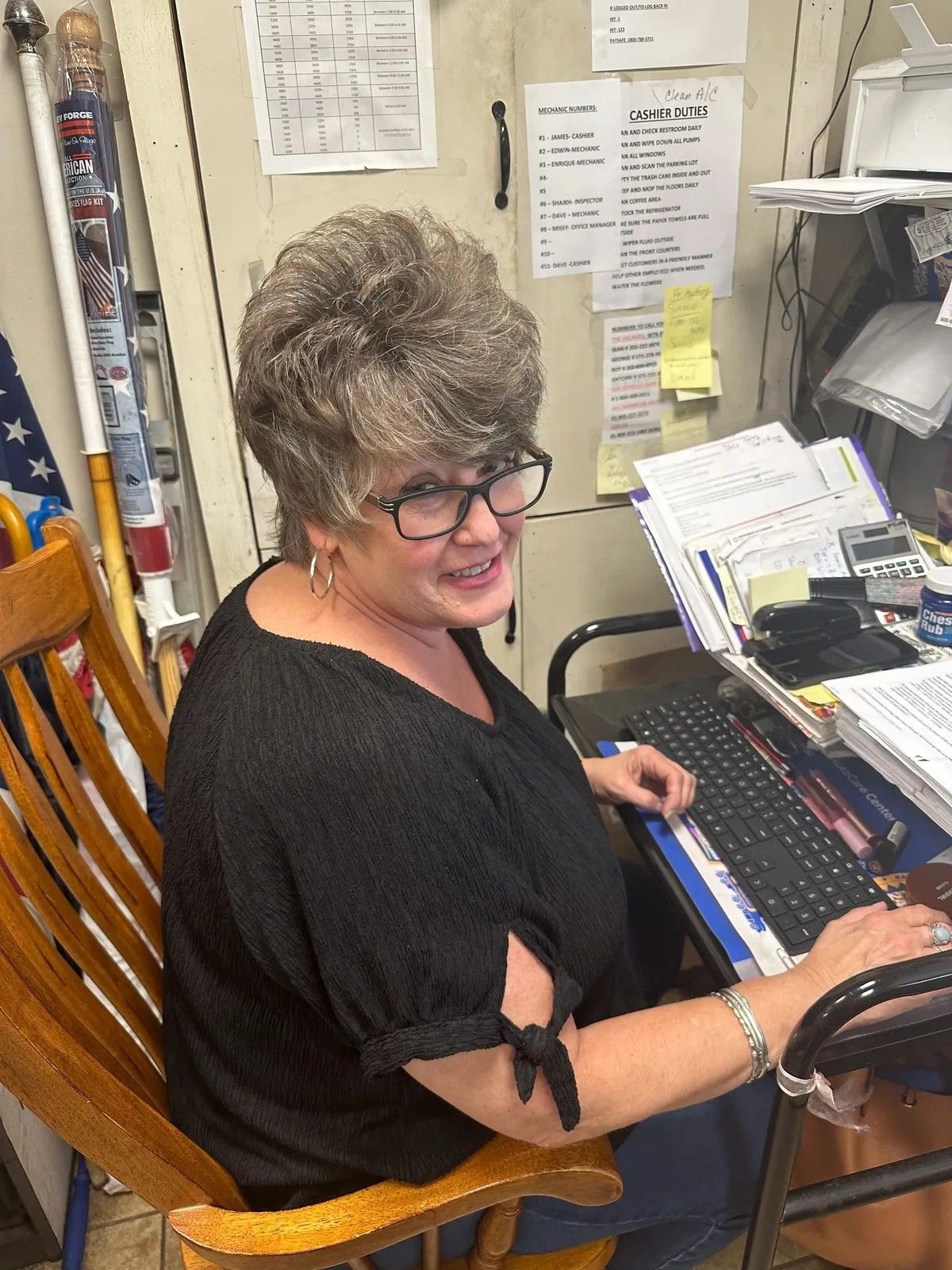 Woman at a desk typing on a keyboard, smiling and looking back in an office workspace.