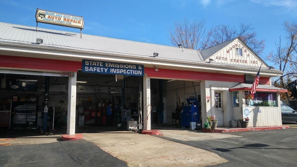 Storefront with open garage bays and a sign reading “State Inspection Safety Inspection” under a blue sky