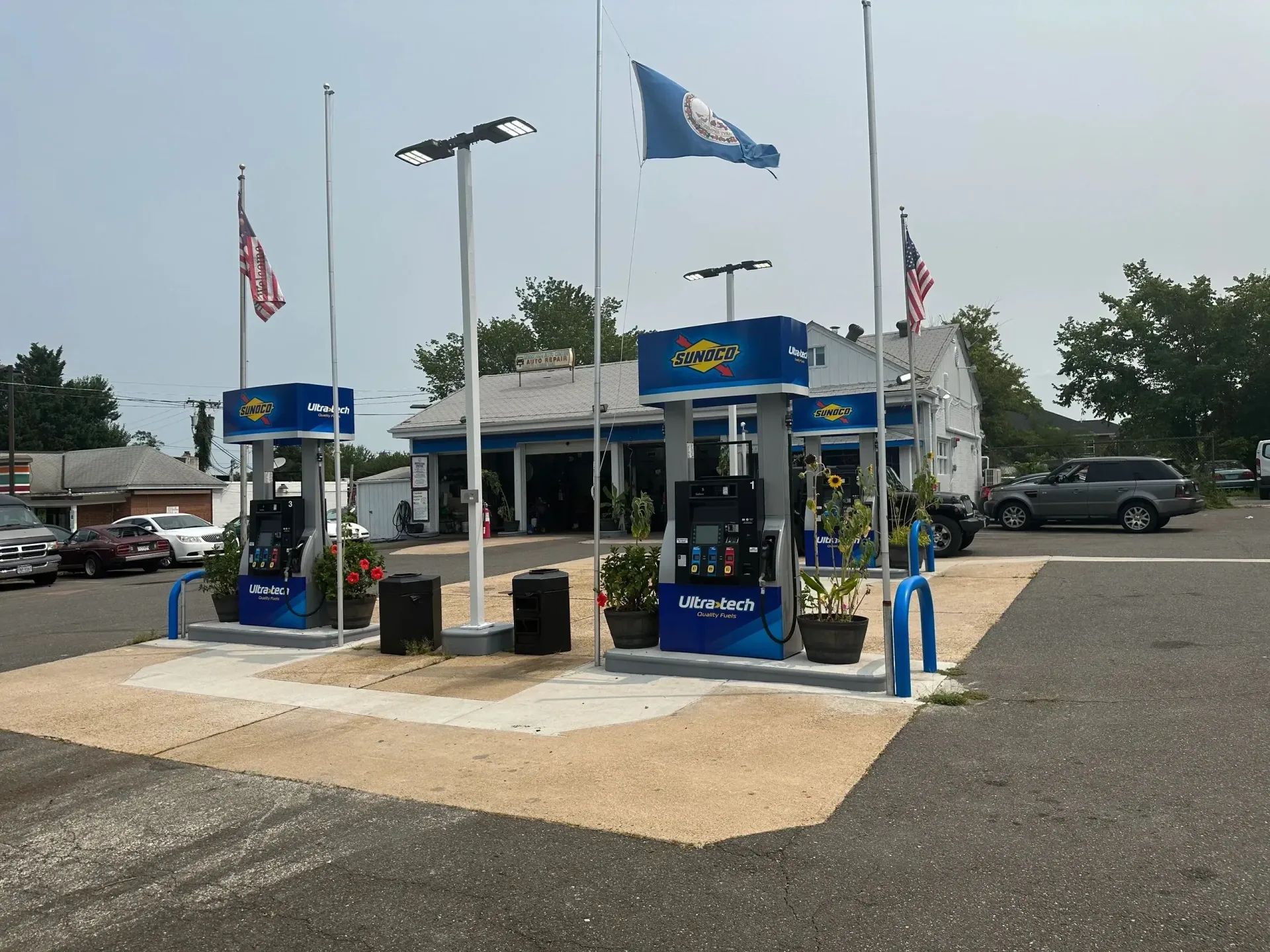 Car wash with blue signage, flags, and vacuum stations on a gravel lot under a clear sky