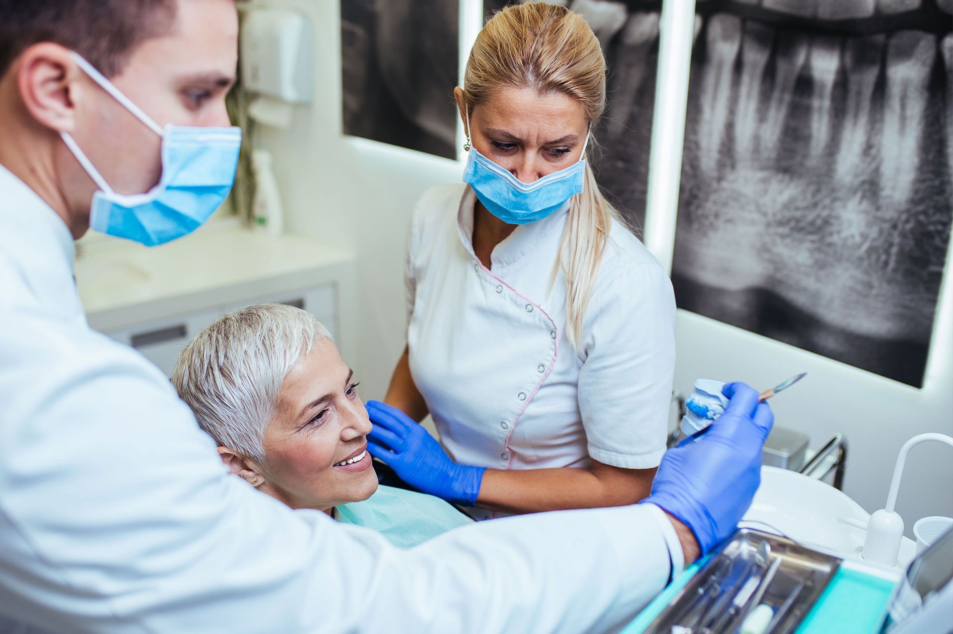 Dentist and assistant examining patient's teeth in a dental office.