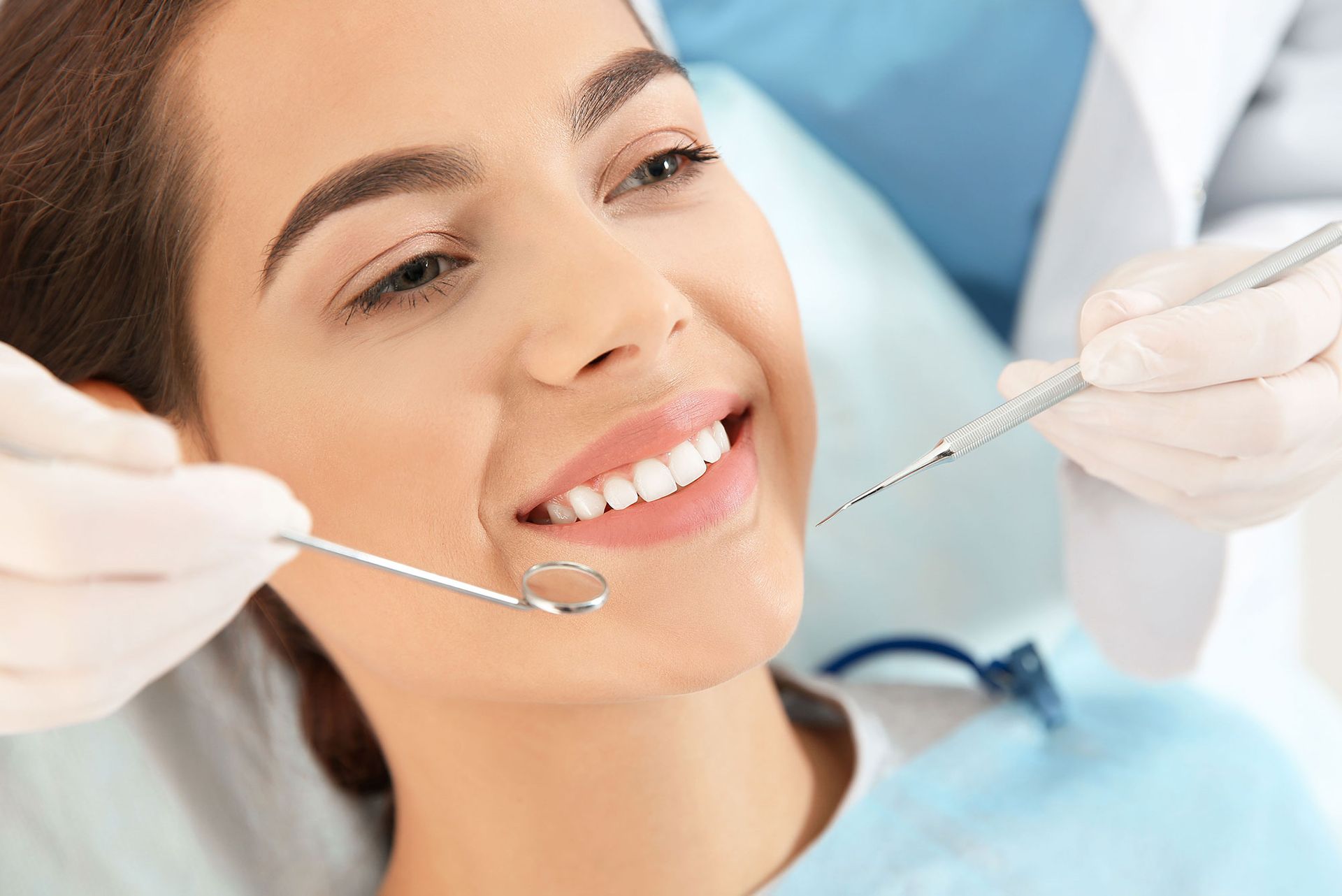 Woman at the dentist with mouth open; dental tools nearby.