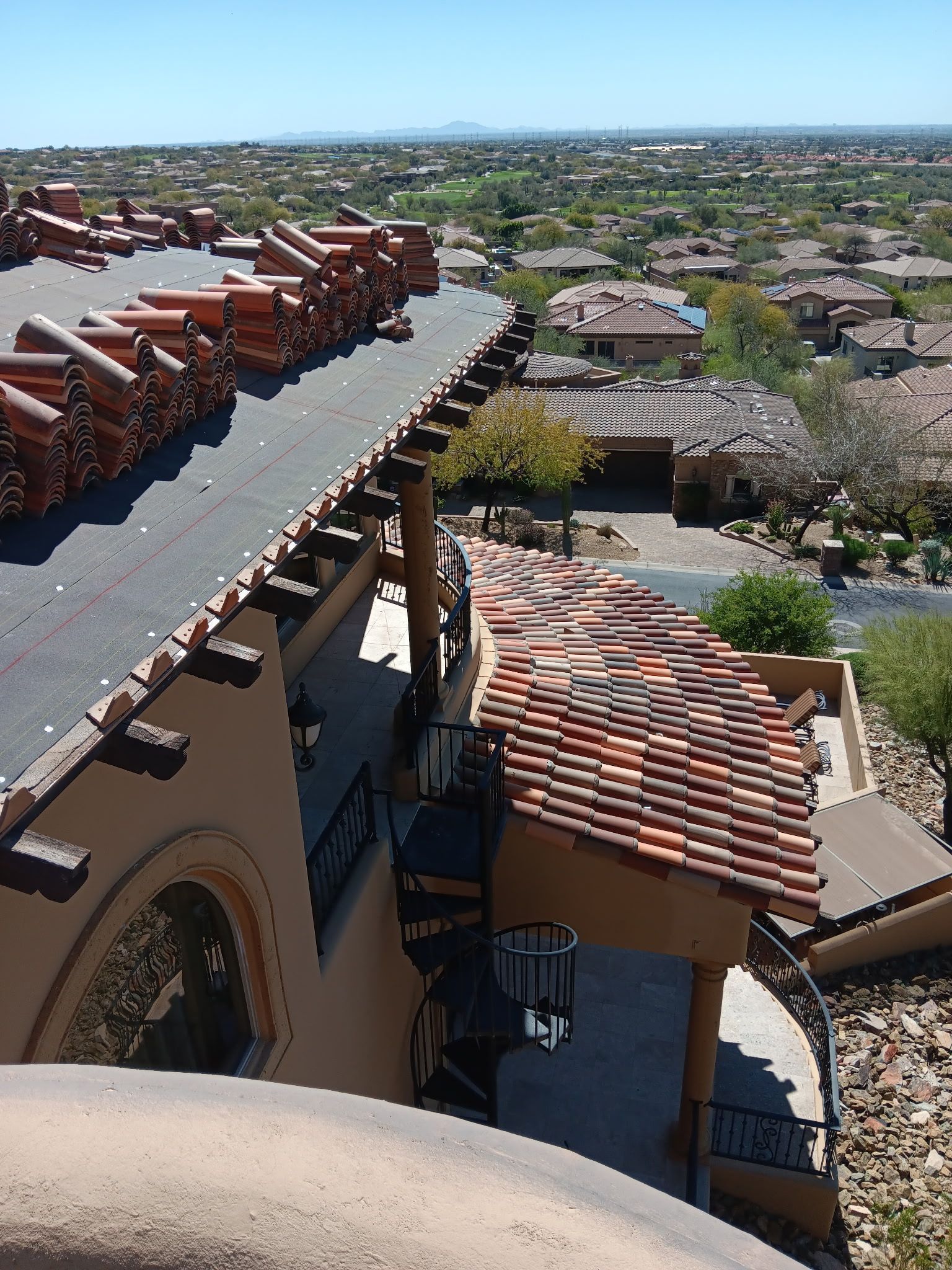 Rooftop view of a terracotta-tiled building overlooking a suburban neighborhood and distant horizon