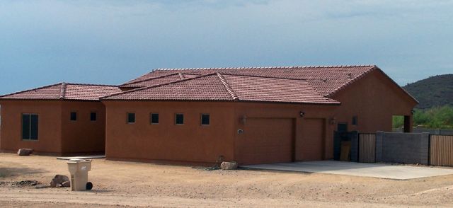 Single-story red-brick building with a corrugated roof and garage doors in a dusty rural area.