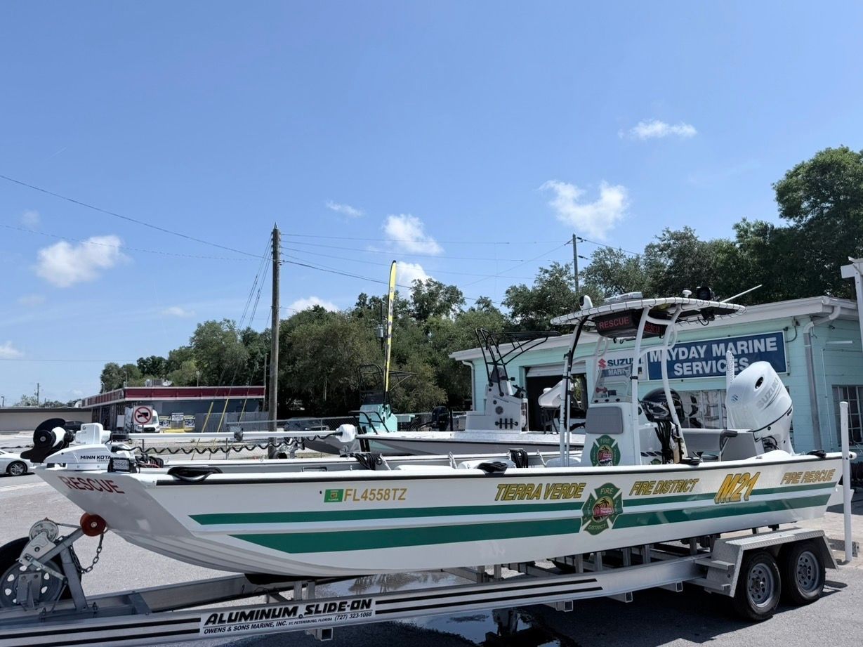 White fishing boat on a trailer by a roadside seafood market under a blue sky