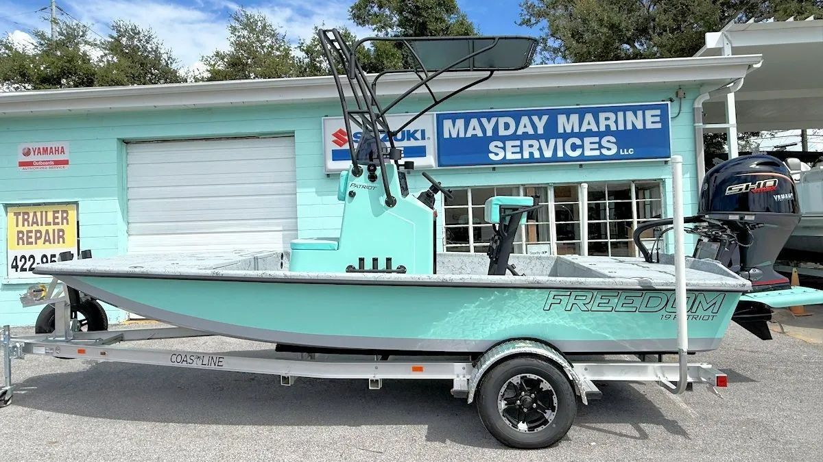 Turquoise boat-shaped storefront with Mayday Marine Services sign and trailer in a parking lot