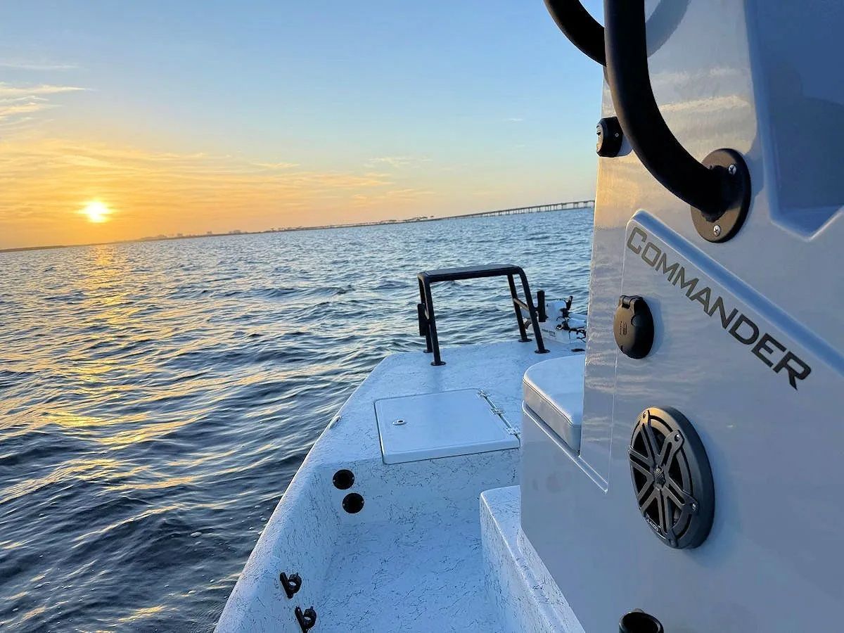 Sunset over calm water beside a white boat deck labeled “COMMANDER”