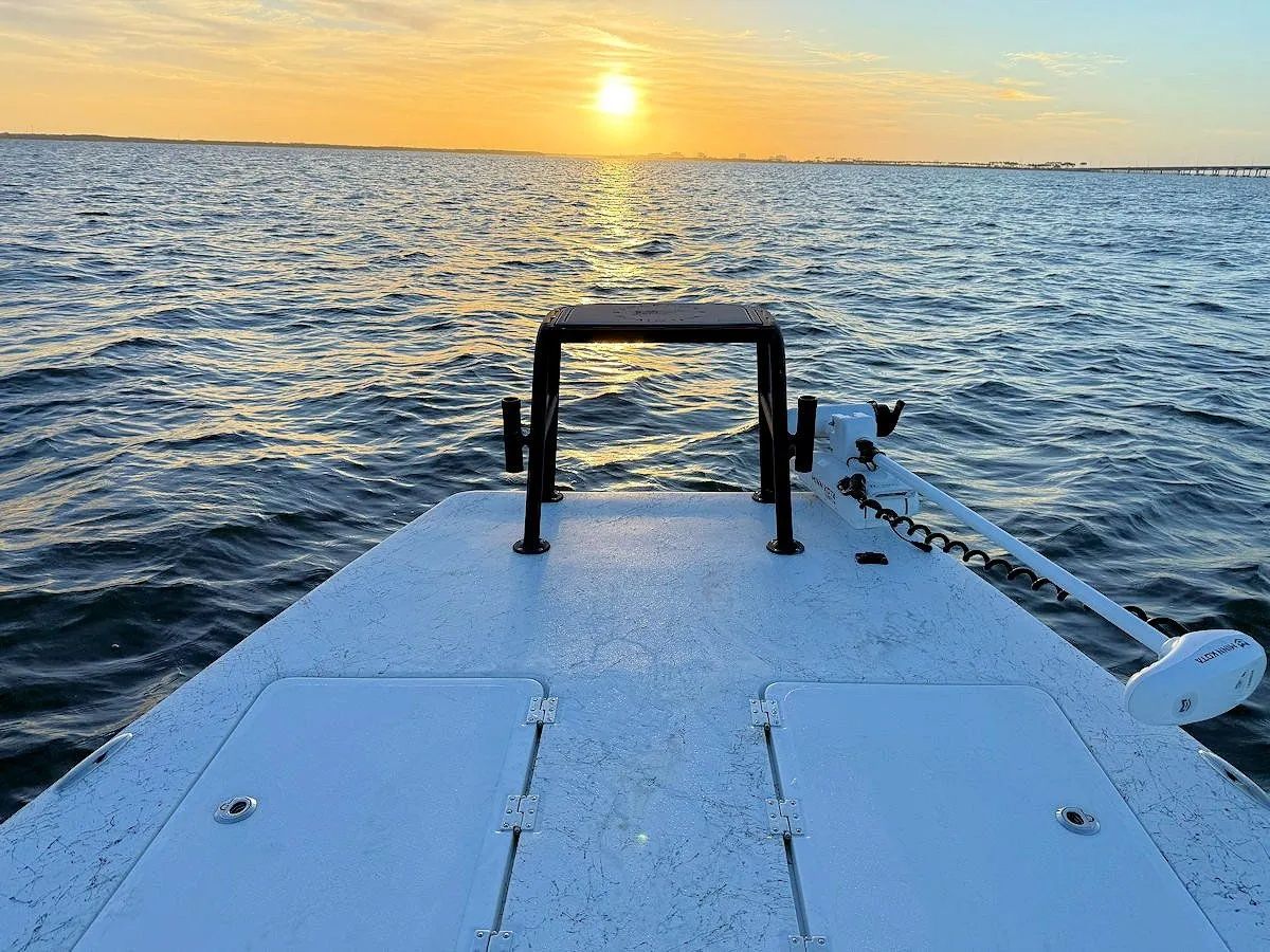 Boat deck facing a sunset over choppy ocean water