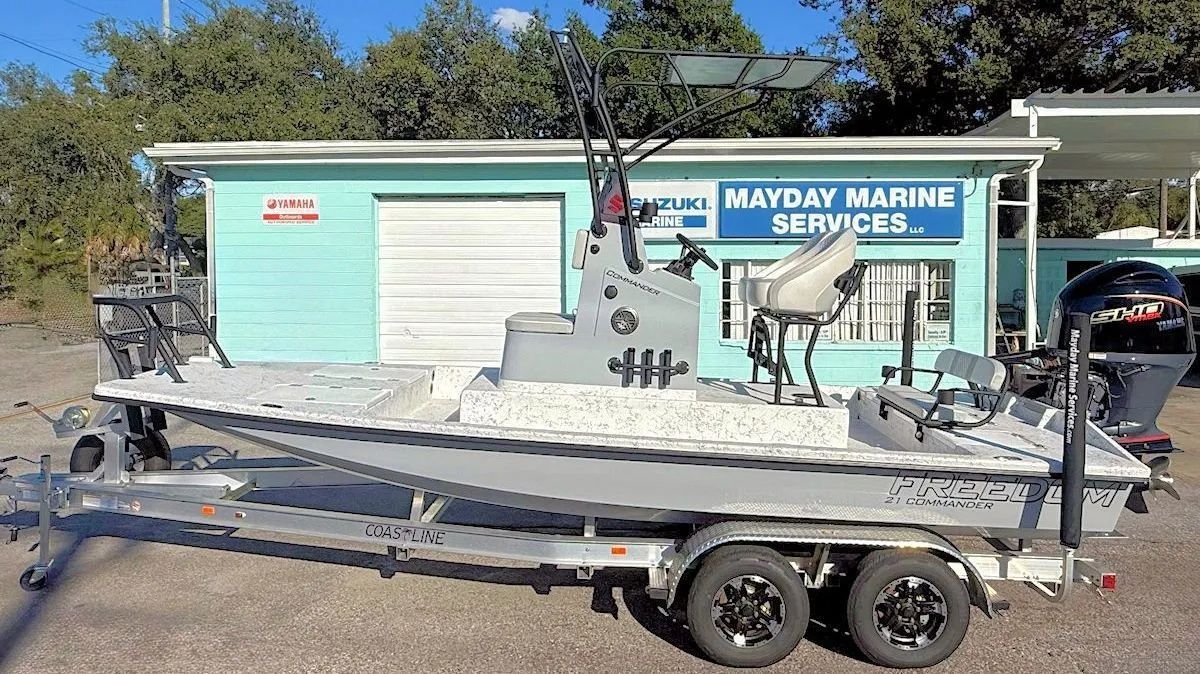 Pontoon boat on a trailer in front of a Mayday Marine Services building.
