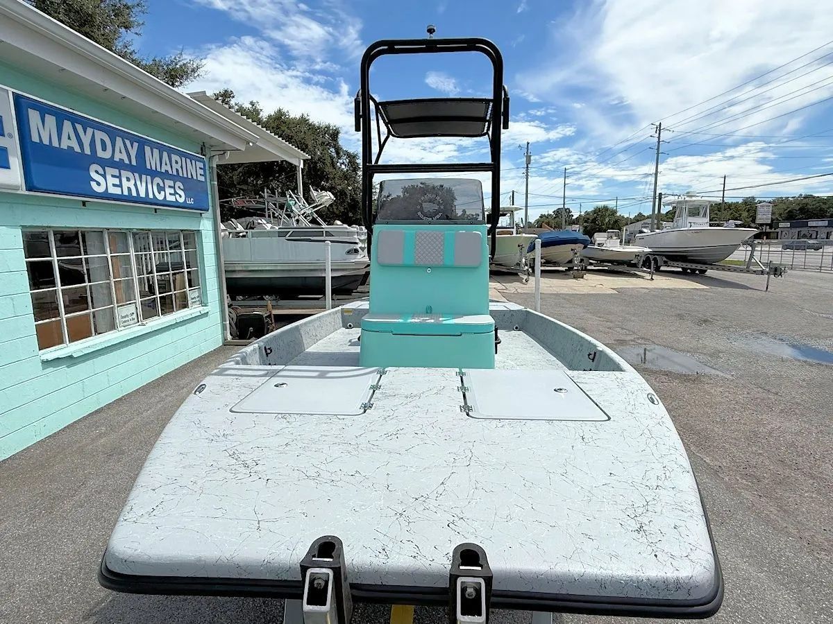 Kayak bow with a cart on a gravel lot beside a turquoise marina service building