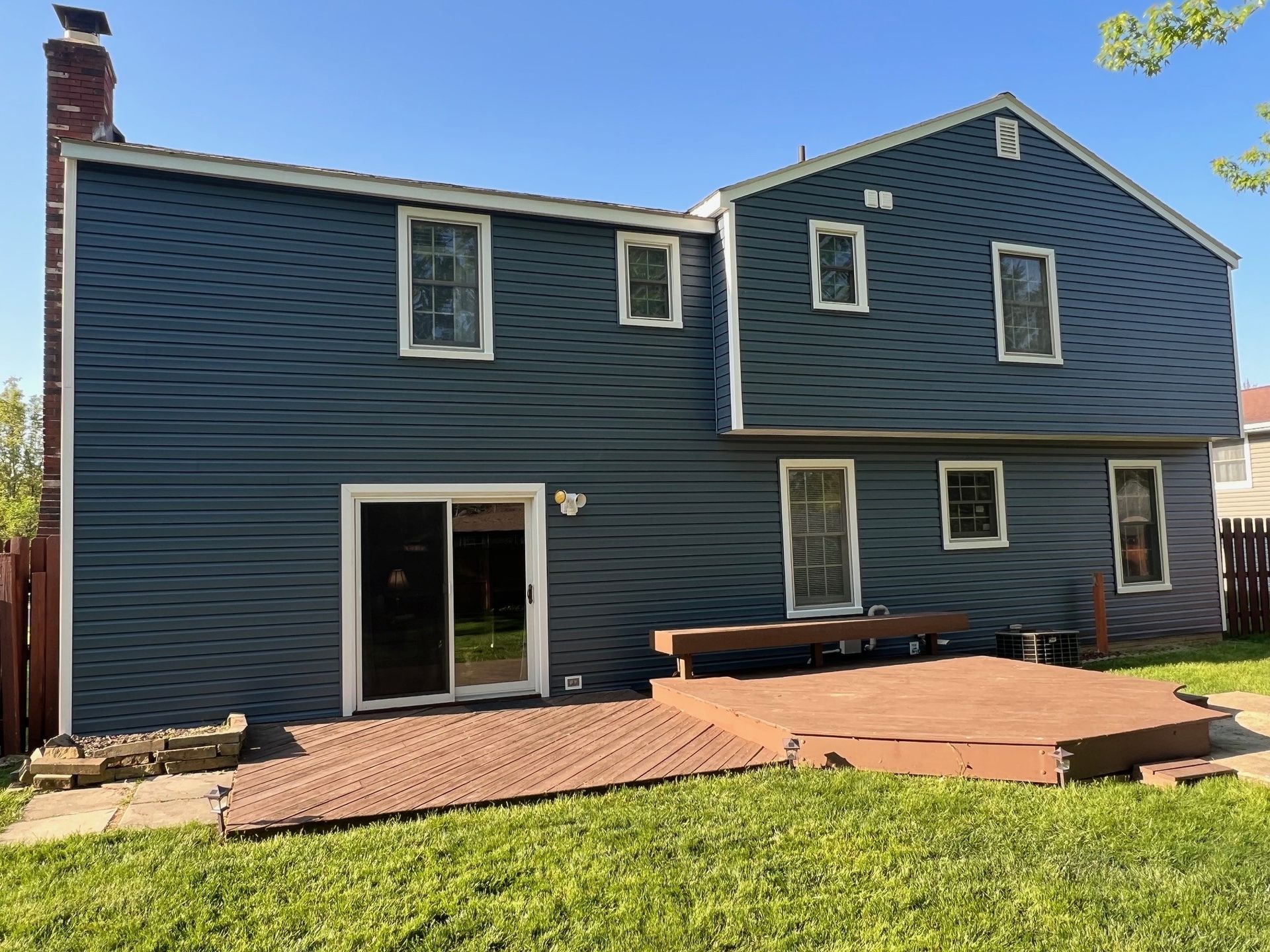 The back of a house with a sliding glass door and a wooden deck.