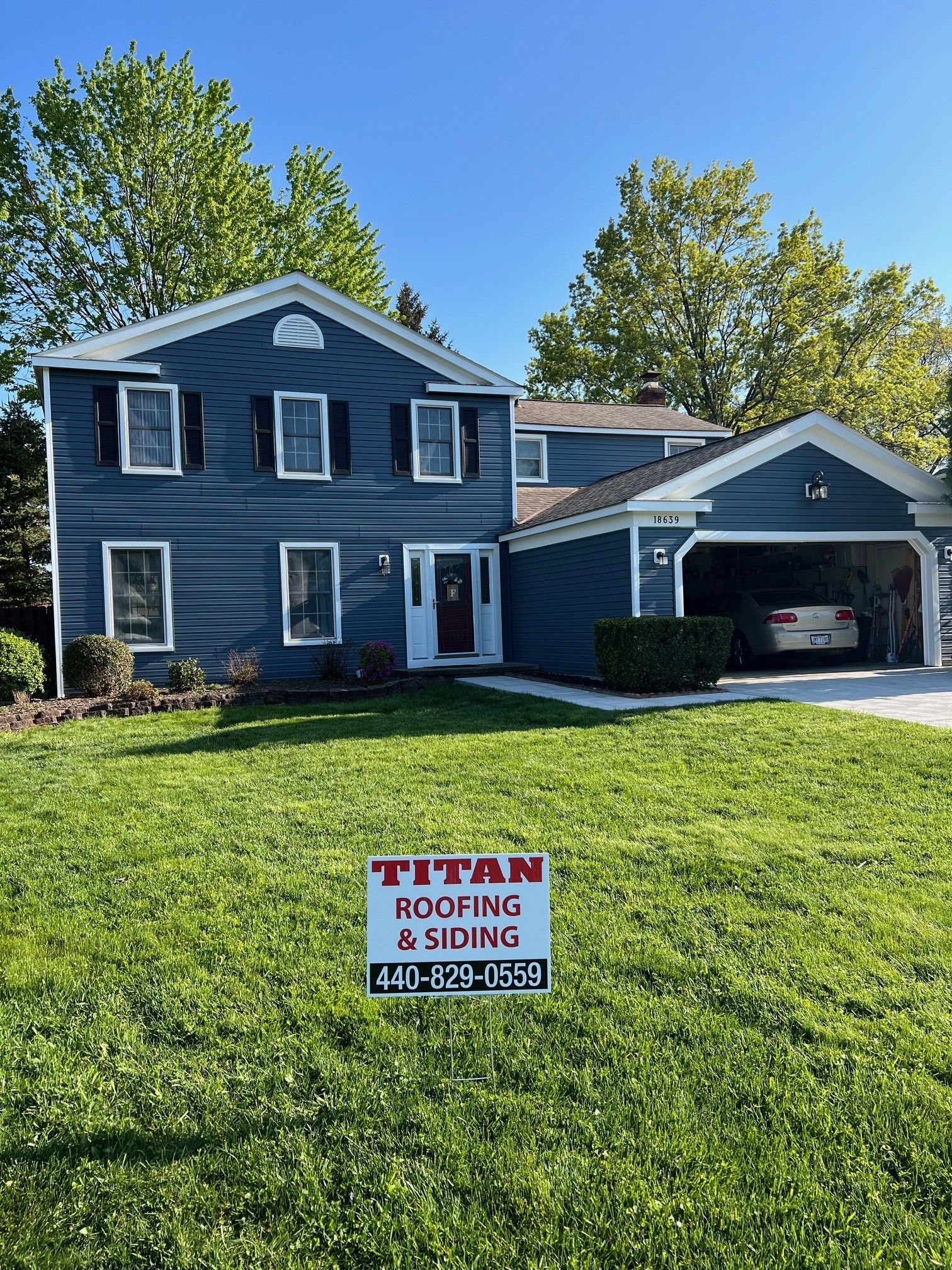 A house with a sign in front of it that says titan roofing and siding.