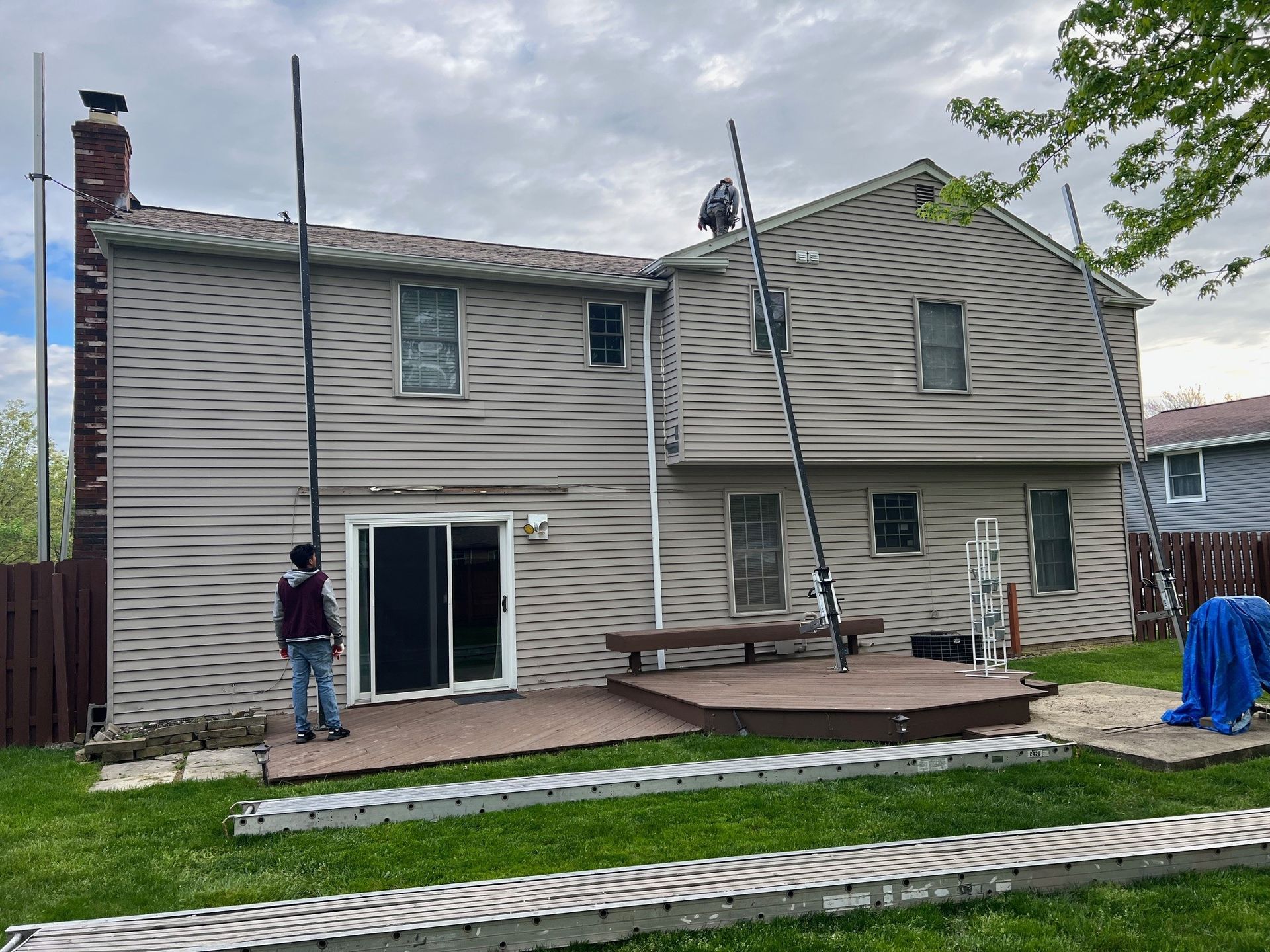 A man is standing on a deck in front of a house.