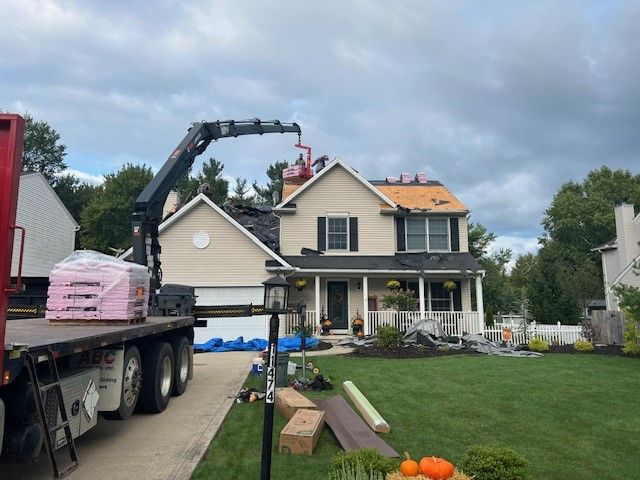 A truck with a crane on top of it is parked in front of a house.