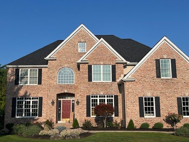A large brick house with black shutters and a red door