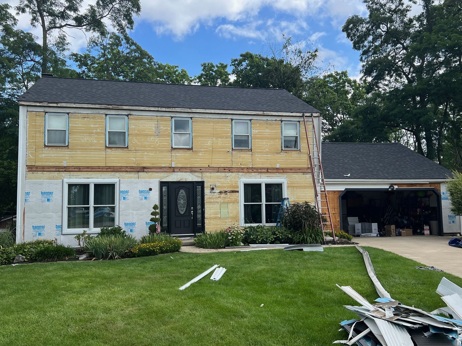 A house is being remodeled with a roof and siding being removed.