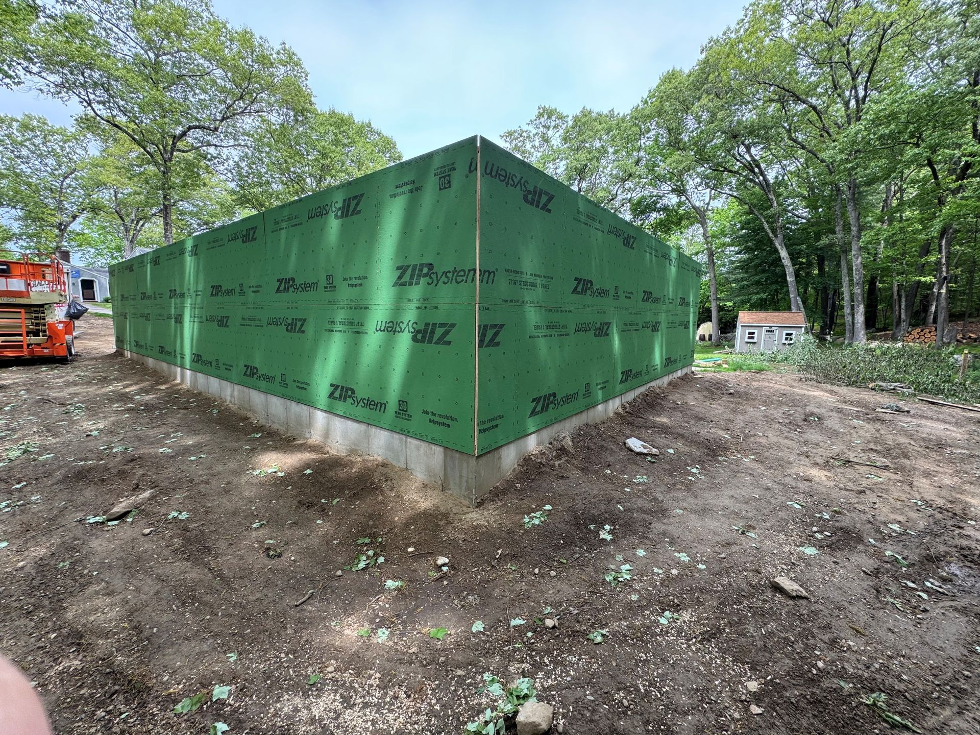Green wrapped house foundation in a wooded construction site