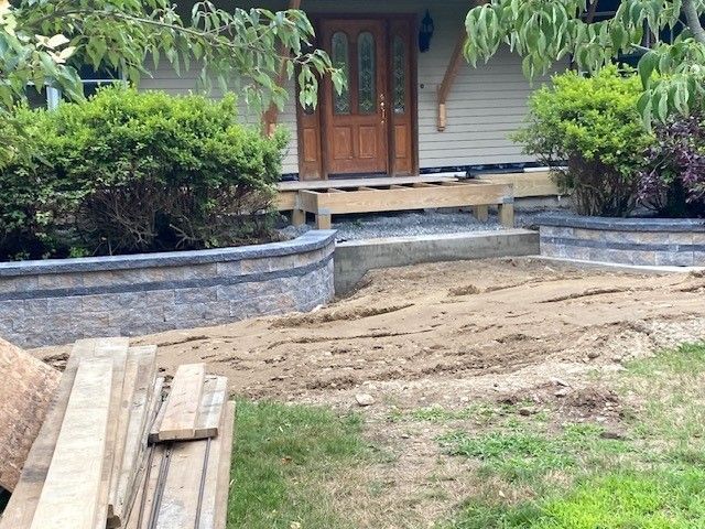 Front yard with dirt path, stone retaining walls, and wooden steps leading to a house porch