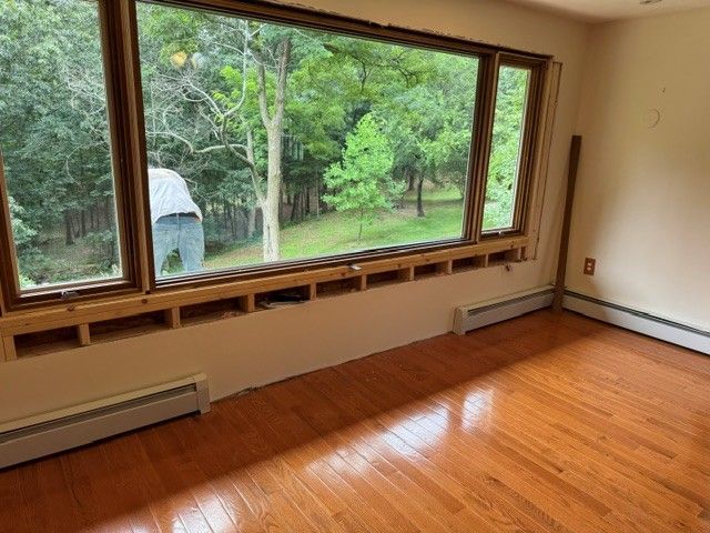 Empty living room with large picture window overlooking a green backyard