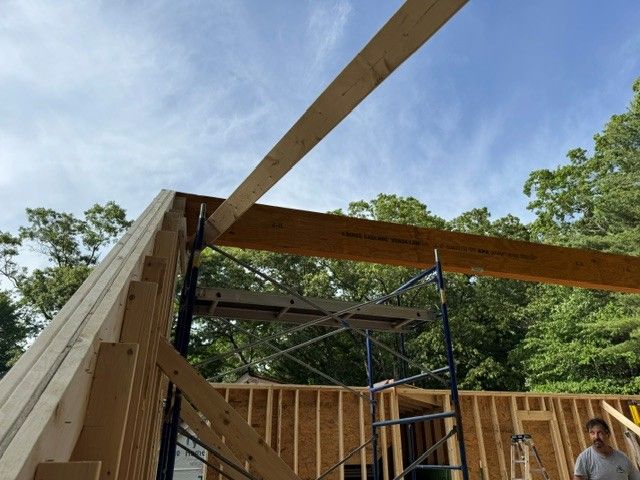 Wooden building frame under construction with scaffolding and workers outdoors